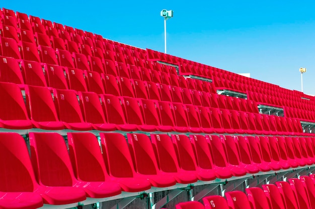 De rijen lege plastic stadionstoelen in rode kleur op het terras