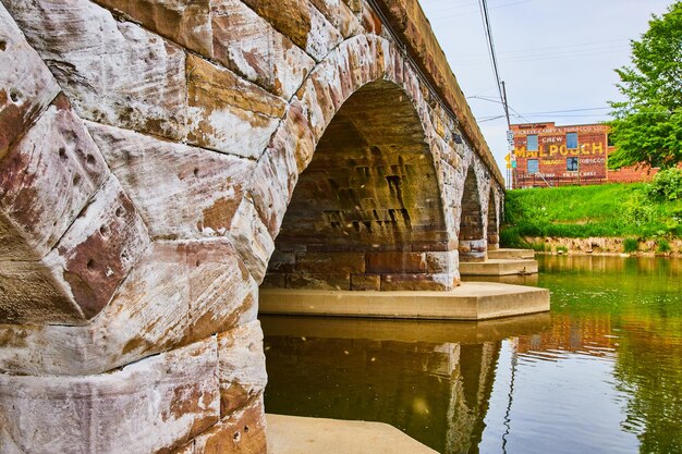 De rivier stroomt onder wit op stenen stenen van aardtoon gouden tinten en gebogen brug