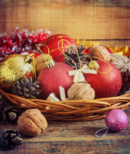 De rode en gele ballen van de Kerstmissamenstelling, kegels, in een mand op houten