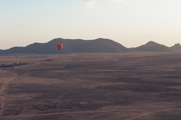 De rode hete luchtballon in het dessert van Marokko in de vroege ochtend