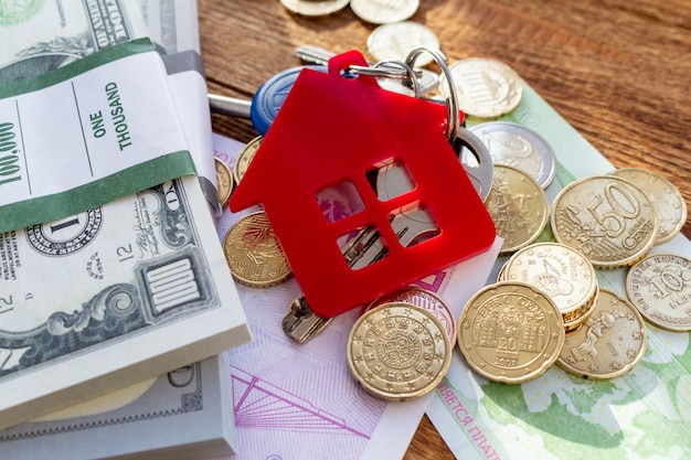 De rode sleutels van het huishuis op de bankbiljetten en muntstukken van het de onroerende goederenconcept van het achtergrondstapelpak het conceptenuitgaven