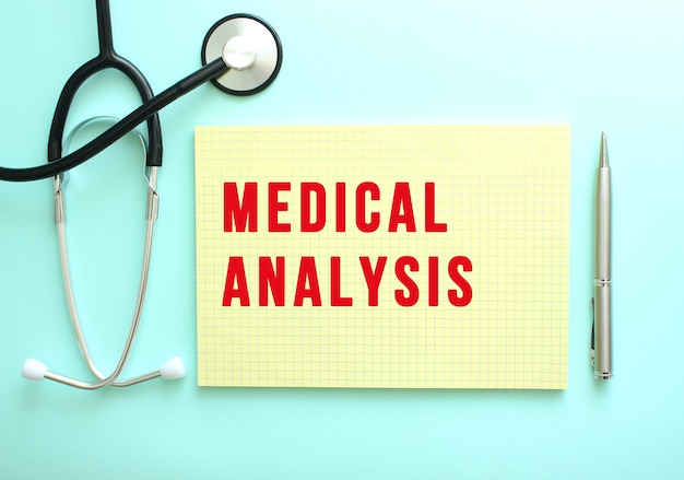 Foto de rode tekst medical analysis is geschreven in een geel blok dat naast de stethoscoop op een blauwe achtergrond ligt.