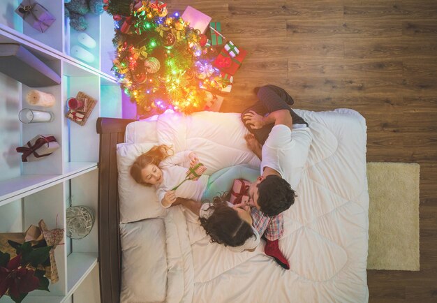 De romantische familie met cadeautjes zit op het bed. uitzicht van boven