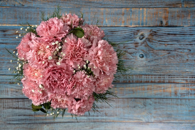 De roze anjer bloeit emmer op blauwe houten achtergrond