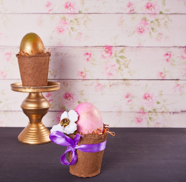 De roze en gouden eieren van Pasen in potten op de lijst