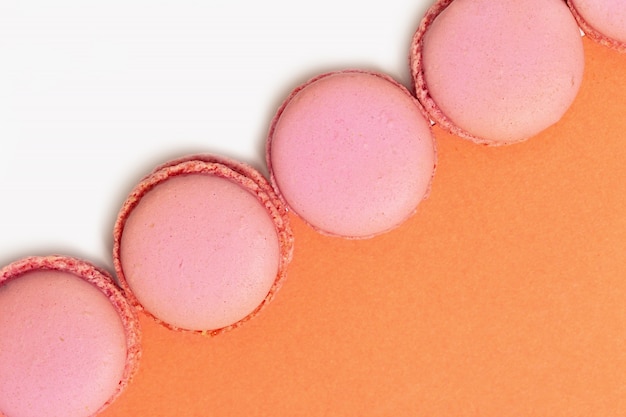 De roze makarons sluiten omhoog op oranje achtergrond. Minimaal creatief concept.