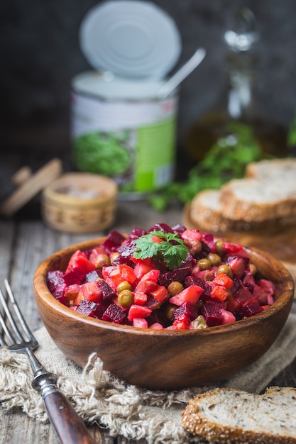 De Russische vinaigrette van de bietensalade in houten kom met roggebrood, rustieke achtergrond