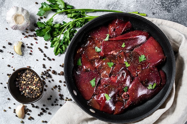 De ruwe lever van Turkije in een pan. Grijze achtergrond. Bovenaanzicht