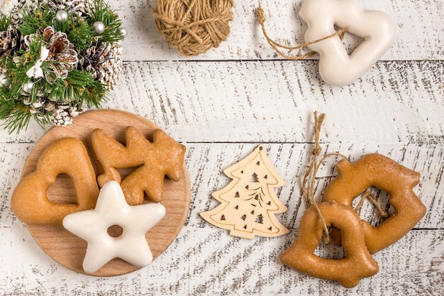 De samenstelling van het nieuwjaar. Gingerbreads, cadeau verpakt in papier en kerstversiering op een witte houten achtergrond. Kerstmis, winter, nieuwjaarsconcept. Platliggend, bovenaanzicht met kopieerruimte.