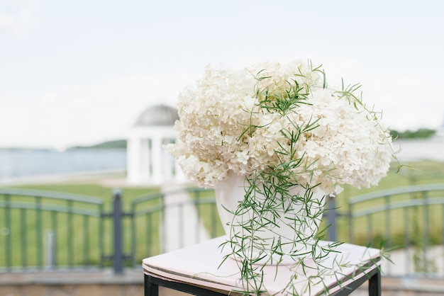 De samenstelling van witte hortensia in een witte bloempot in het decor van de huwelijksregistratie van het huwelijk