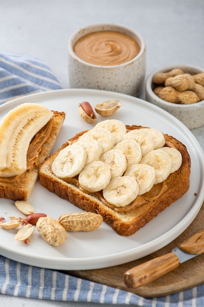 De sandwich van de pindakaasbanaan in een witte plaat op grijze achtergrond