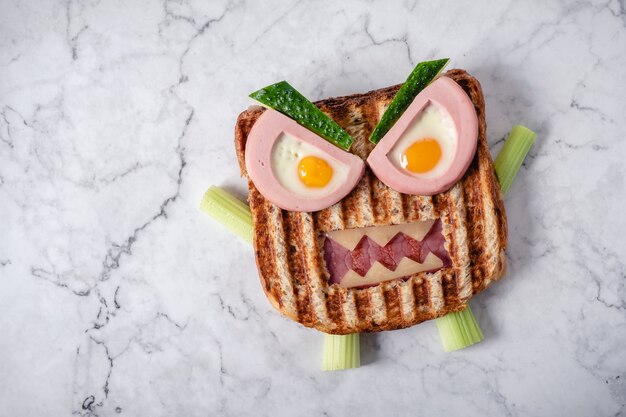 De sandwich van het prethalloween-monster met de worst, de eieren en de kaas van het plakvlees op plaat