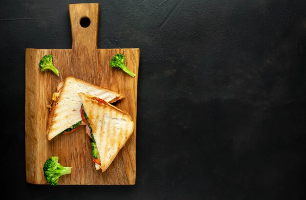 De sandwiches van de broccolikaas op houten scherpe raad, op beton, leiachtergrond