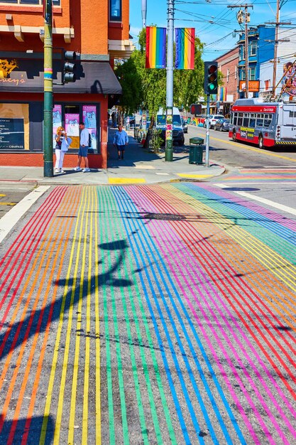De schaduw van een telefoonpaal valt over het regenboogzebrapad met LGBTQ-spandoeken