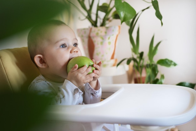 De schattige baby bijt een groene appel