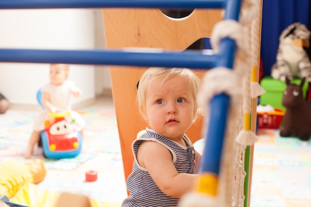 De schattige baby die op de speelplaats op de kleuterschool speelt