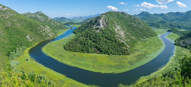 De schilderachtige meanderende rivier stroomt tussen groene bergen.