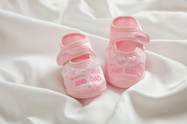 De schoenen van het babymeisje op de witte ruimte van het satijnexemplaar