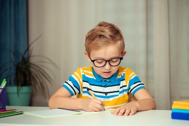 De schooljongen doet zijn huiswerk thuis aan tafel