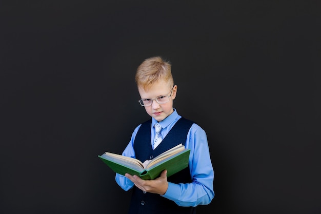 De schooljongen leest een boek op het schoolbestuur