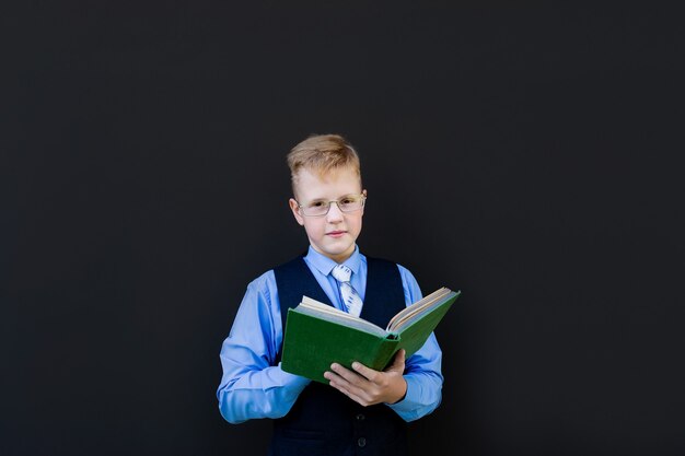 De schooljongen met een boek op een zwarte achtergrond