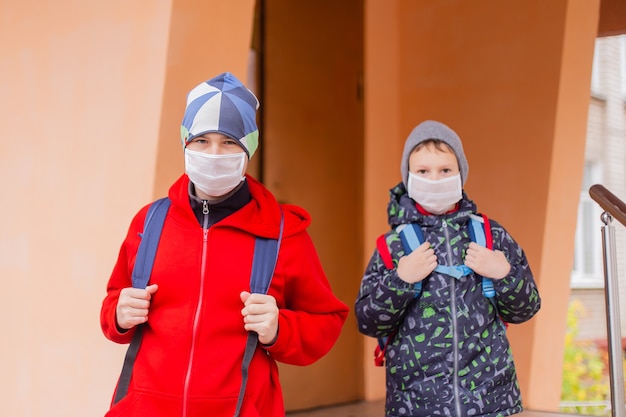 De schooljongen van de jongen loopt de school uit die beschermend masker draagt