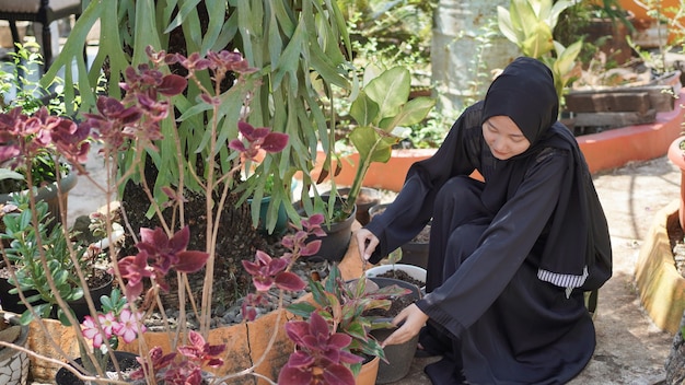 De schoonheid in hijab die graag bloemen plant in de tuin