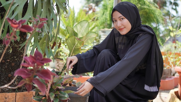 De schoonheid in hijab die graag bloemen plant in de tuin