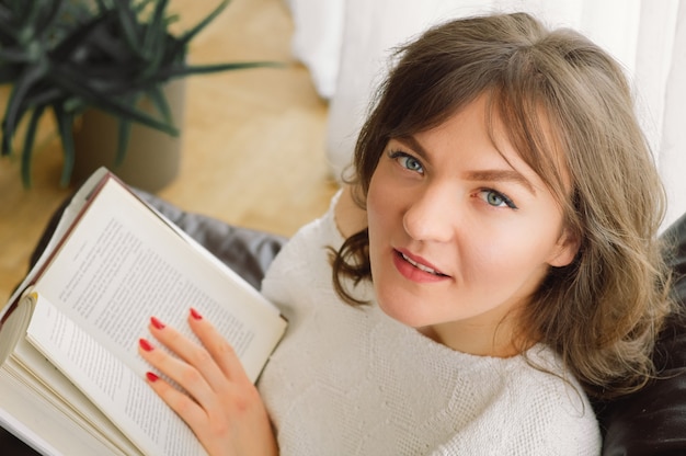 De schoonheids jonge vrouw leest thuis een boek