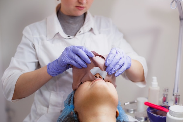 De schoonheidsspecialist verwijdert het masker van het gezicht van de klant in de schoonheidssalon