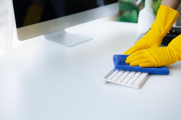 De schoonmaakmedewerker van de persoonsschoonmaakruimte gebruikt een doek om het toetsenbord van de computer in de kantoorruimte van het bedrijf af te vegen Schoonmaakpersoneel Concept van reinheid in de organisatie