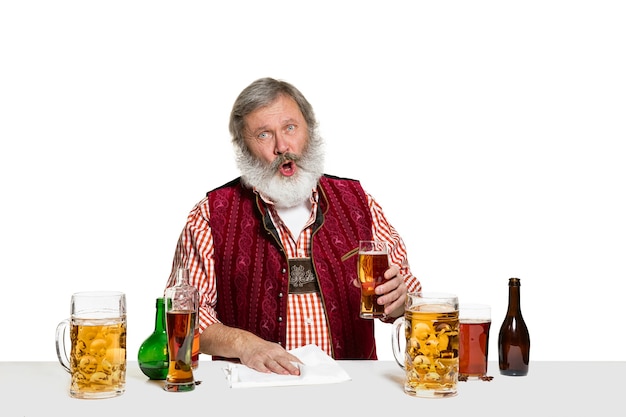 De senior deskundige mannelijke barman met bier geïsoleerd op een witte muur. Internationale barman dag, bar, alcohol, restaurant, bier, feest, pub, St. Patrick's Day viering concept