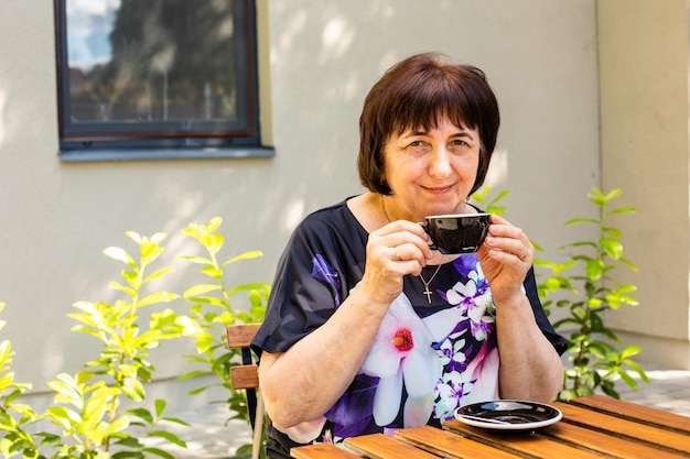 De senior vrouw ontspant in het straatcafé