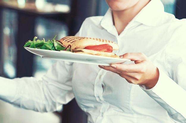 De serveerster draagt een bord eten naar de klant