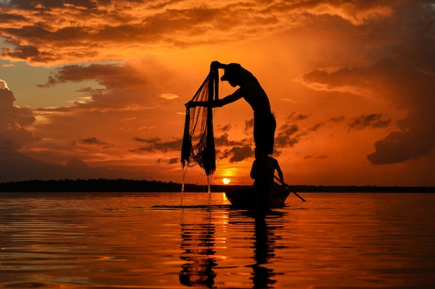 De silluate vissersboot in de rivier tijdens zonsopgang, Thailand