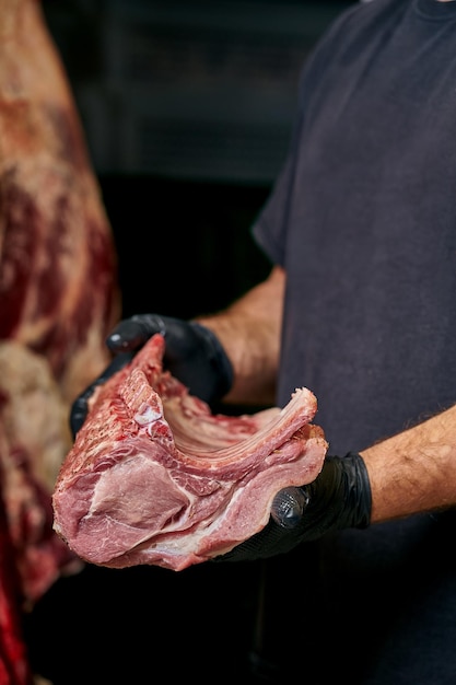Foto de slager houdt een stuk varkensvelg vast.