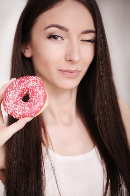 De slanke vrouw houdt in hand roze doughnut