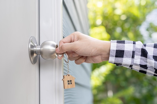 De sleutel van de verhuurder voor het ontgrendelen van het huis is in de deur gestoken. Tweedehands huis te huur en te koop Eigenaar gebruikt de deur met de hand ontgrendelen hypotheek voor nieuw huis kopen verkopen renoveren investering eigenaar landgoed