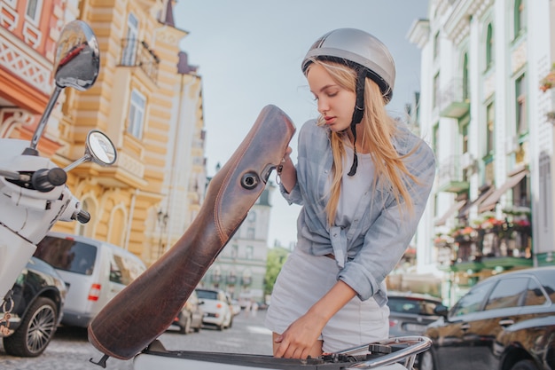 Foto de slimme en knappe vrouw kijkt onder motorfietszetel