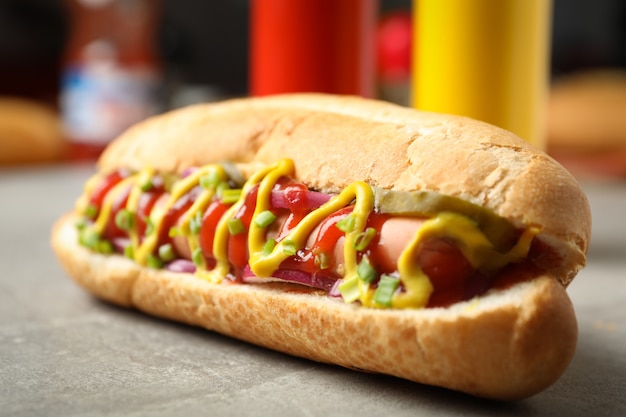 De smakelijke hotdog op grijze lijst, sluit omhoog