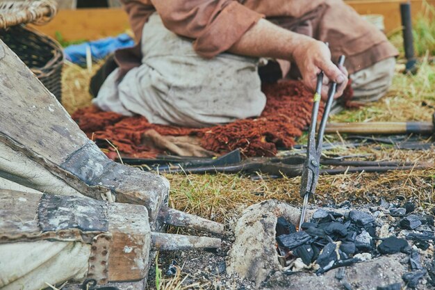 De smid warmt het werkstuk op met blaasbalgen op het vikingfestival in Denemarken