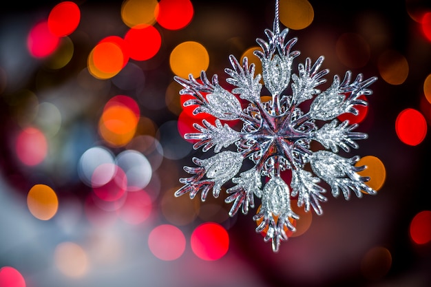 De sneeuwvlokdecoratie van de kerstboom op lichtenachtergrond