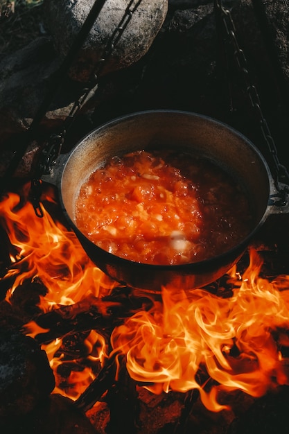 De soep wordt gekookt boven een vuur in een ketel
