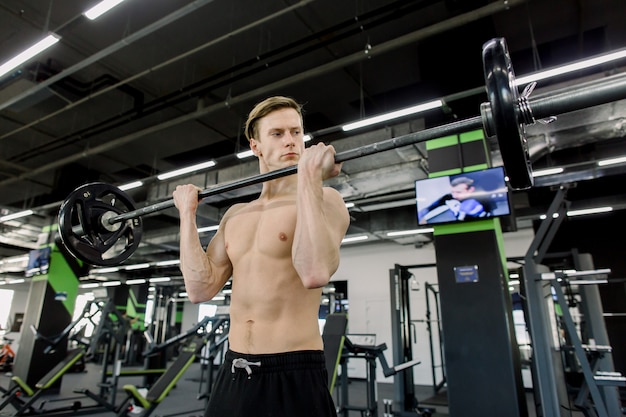 De spieren van de jonge mensenverbuiging met barbell in gymnastiek