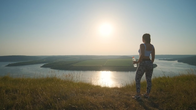 De sportieve vrouw die op een prachtige rivierachtergrond staat