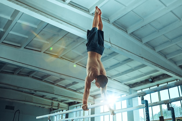 De sportman die moeilijke gymnastiekoefeningen uitvoert in de sportschool de sportoefening