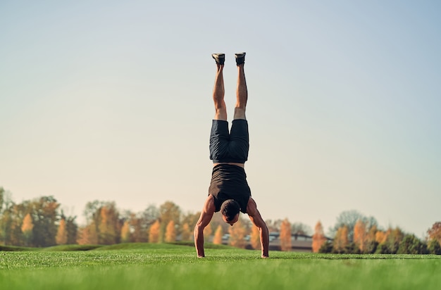 De sportman staat op handen op het gras