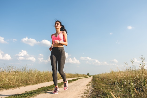 De sportvrouw die op het veldpad loopt