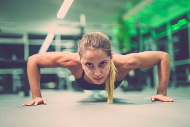 De sportvrouw doet push-up oefening in de sportschool