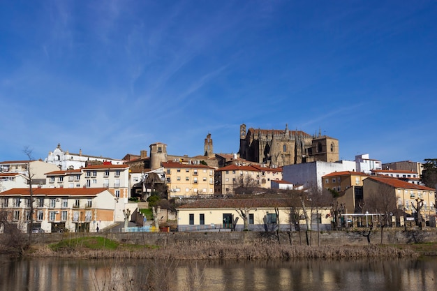 De stadshorizon van Plasencia met de Jerte-rivier op de voorgrond en de kathedraal en andere historische gebouwen op de achtergrond